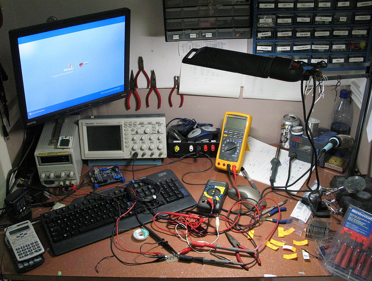 Electronics workshop and retail bench with multimeters, power supplies, testing equipment, and repair tools